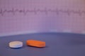 Pills of colors in a neutral background. Electrocardiogram strip out of focus