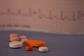 Pills of colors in a neutral background. Electrocardiogram strip out of focus