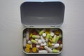 Pills of different color inside a metal box on a wood table Royalty Free Stock Photo