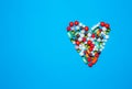 Pills of different colors lie in the shape of a heart on a blue background of a flat shape. medical texture with medicines,