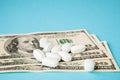 Pills on dollar money on blue background. Medicine expenses. High costs of medication concept. Close up Royalty Free Stock Photo