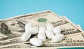 Pills on dollar money on blue background. Medicine expenses. High costs of medication concept. Close up Royalty Free Stock Photo