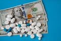 Pills on dollar money on blue background. Medicine expenses. High costs of medication concept. Close up Royalty Free Stock Photo