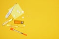 Pills, electronic thermometer, ampoules with medicine and a syringe on a yellow background copy space top view