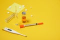 pills, electronic thermometer, ampoules with medicine and a syringe on a yellow background copy space top view