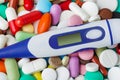 Pills and electronic thermometer with blank screen - medical background Royalty Free Stock Photo