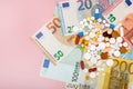 A pills and euro on a pink background with copy space. Soft focus. Concept of medicine, money and health