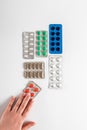Pills in a female hand on a background of colorful pills and capsules in blister packs on a white background. Coronavirus. Royalty Free Stock Photo