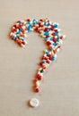 Pills forming a question mark on a wood bleached