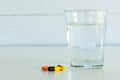 Pills and a glass of drinking water isolated on the white table Royalty Free Stock Photo