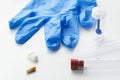 Pills, glass tubes, stool test sampler and blue latex glove on white