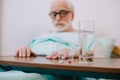 Pills and glass of water in front of senior man Royalty Free Stock Photo