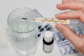 Pills, glass of water and thermometer in hand on white background