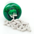 Pills with green medicine bottle on white background
