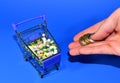 Pills and hand with money on blue background. Coins for payment of medicines. Shopping cart with pills. Medicine tablets and