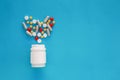 Pills heart out of pill bottle on blue background, top view Royalty Free Stock Photo