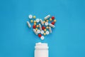 Pills heart out of pill bottle on blue background, top view Royalty Free Stock Photo