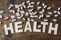 Pills with inscription Health on wooden surface background