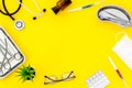 Pills and instruments of doctor frame on yellow background top view copyspace