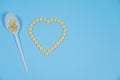 Pills - medicines are poured in the form of heart on a blue background and spoon Royalty Free Stock Photo