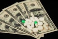 Pills with money Expensive medicine. Covid-19 coronavirus pills are scattered across the hundred dollar bills. A handful Royalty Free Stock Photo