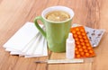 Pills and nose drops for colds, handkerchiefs and hot tea with lemon