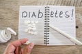 Pills and notebook with pen on a wooden background. Diabetes concept. The inscription `diabetes` on a notebook. View from above.