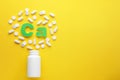 Pills, open bottle and calcium symbol made of green letters on yellow background, flat lay. Space for text Royalty Free Stock Photo