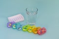 Pills in a plastic pill boxes for 7 days of a week with glass of water on blue background Royalty Free Stock Photo