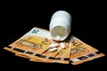 Pills pour out of a pill bottle on the euro banknotes, representing the high cost of health care and medication concepts. Royalty Free Stock Photo