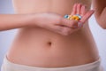 Pills with probiotics on the background of the female abdomen.