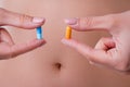 Pills with probiotics on the background of the female abdomen.