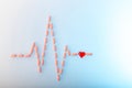 Pills in shape of cardiogram pulse on blue gradient background. Vitamins and red glass heart, symbol of healthy lifestyle.