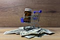 Pills in a shopping basket on a heap of American dollars. Economy concept of spending money on medicines and pills. Medical pill