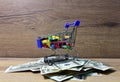 Pills in a shopping basket on a heap of American dollars. Economy concept of spending money on medicines and pills. Medical pill