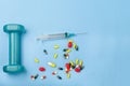 Pills small Dumbbell and disposable syringe closeup on blue background. medicine sport pharmacology concept Royalty Free Stock Photo