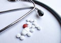 Pills spilled out of a pill bottle with a stethoscope in the frame and isolated on white background. Top view with copy space. Royalty Free Stock Photo