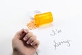 Pills Spilling out of Bottle near Womans hand near sorry note, implication suicide overdose, posed studio shot