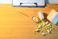 Pills spilling out of pill bottle with doctor clipboard