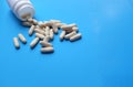 Pills spilling out of pill bottle and isolated on blue. Medicine concept Royalty Free Stock Photo