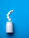Pills spilling out of pill bottle and isolated on blue. Top view Royalty Free Stock Photo