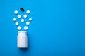 Pills spilling out of pill bottle and isolated on blue. Top view Royalty Free Stock Photo