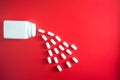 Pills spilling out of pill bottle and isolated on red. Top view with copy space. Medicine concept Royalty Free Stock Photo