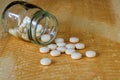 Pills spilling out of pill bottle on table Royalty Free Stock Photo