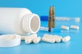Pills spilling out from White container. Medical containers, Pills, Syringe, ampoules for injections on a blue medical background