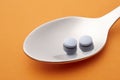 Pills and spoon detail. Orange background. Medicament treatment.