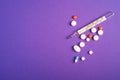 Pills, tablets and analog thermometer on violet purple background, healthcare medical concept, antibiotics and cure Royalty Free Stock Photo