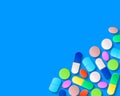 Pills, tablets and capsules in the lower right corner on a blue background