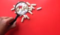 pills, tablets, capsules under the magnifying glass on red background. Minimal modern pharmacy or health care concept. Flat lay Royalty Free Stock Photo