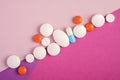 Pills and tablets in diagonal row on bright pink, violet and purple background, healthcare medical concept Royalty Free Stock Photo